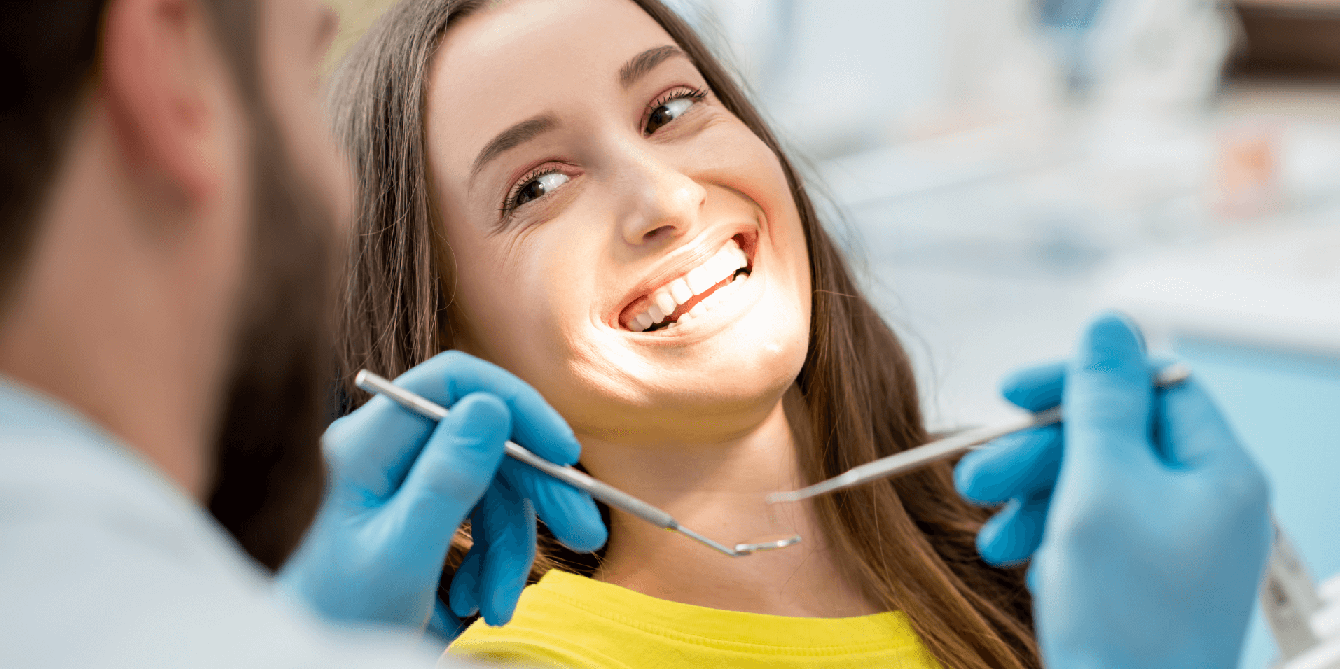 Young woman smiling while a dentist performs a routine dental checkup.