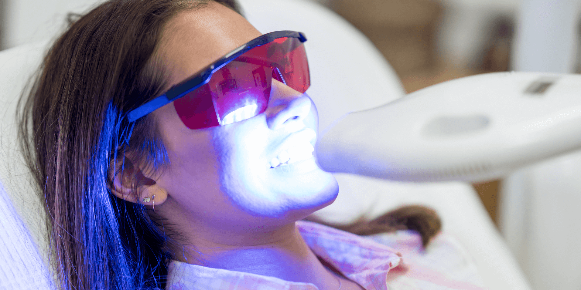 Patient receiving professional teeth whitening treatment with LED light